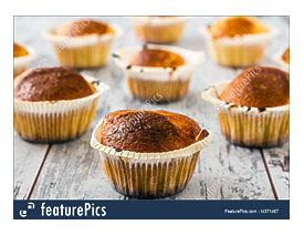 Muffins With Candle In Paper Cupcake Holders On Wooden White Table